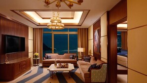 A spacious living room with a large flat-screen TV, a sofa set, a coffee table, and a view of the ocean. - Royal M Al Aqah Beach Hotel And Resort by Gewan (Al Aqah)