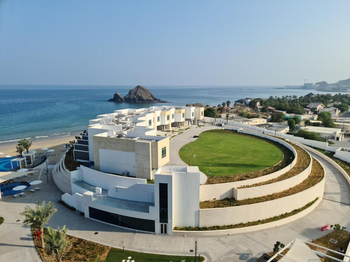 A modern hotel with a central courtyard, pool, and ocean view.