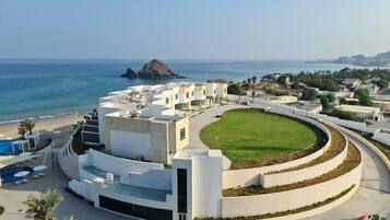 A modern hotel with a central courtyard, pool, and ocean view.