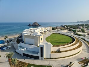 A modern hotel with a central courtyard, pool, and ocean view.