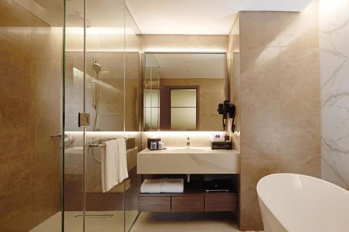 Un baño moderno con cabina de ducha de vidrio, tocador con espejo y bañera independiente.