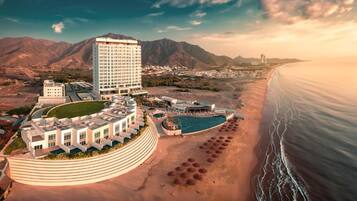 Un complexe hôtelier comprenant un grand bâtiment, une piscine et une plage.