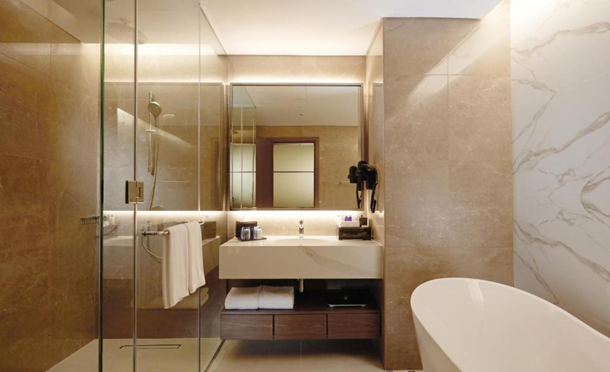 A modern bathroom with a glass shower enclosure, a vanity with a mirror, and a freestanding bathtub.