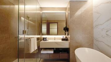 A modern bathroom with a glass shower enclosure, a vanity with a mirror, and a freestanding bathtub.