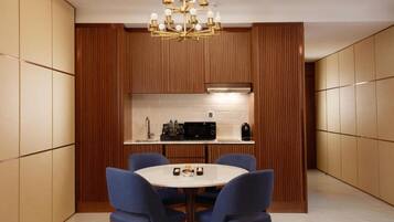 Une cuisine moderne avec un lambris en bois, une table de salle à manger ronde entourée de chaises bleues et un lustre.