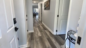 A hallway with white walls, a gray and white patterned rug, and a door with a black handle. - Minutes to beach and golf courses (Myrtle BEach)