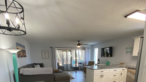 A modern kitchen with a dining area, a sofa, and a TV mounted on the wall. - Minutes to beach and golf courses (Myrtle BEach)