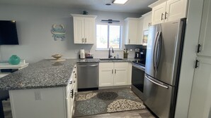 A modern kitchen with white cabinets, a stainless steel refrigerator, and a granite countertop. - Minutes to beach and golf courses (Myrtle BEach)