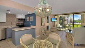 A modern kitchen with a central island, a dining area with wicker furniture, and a large chandelier. - Relaxing beachfront getaway ocean heated pool U4 (Marathon)