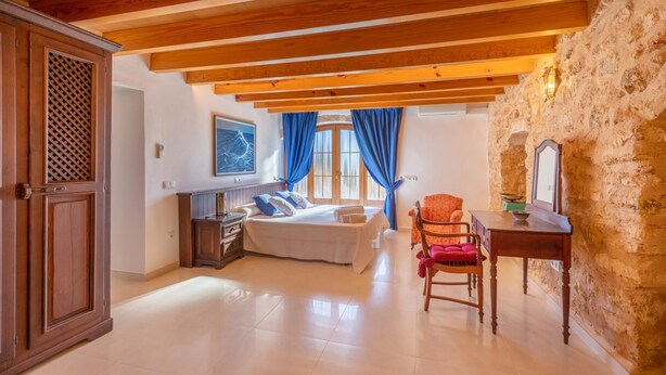 Un dormitorio con cama, cómoda, silla y mesa.
