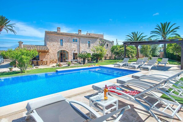 A poolside area with lounge chairs and a stone building in the background.