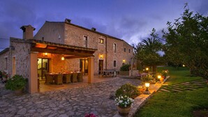 Un edificio de piedra con un patio, mobiliario exterior y plantas en macetas.