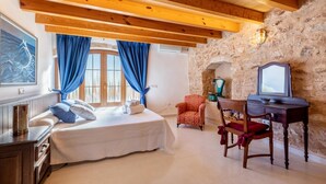 Un dormitorio con una cama, un escritorio, una silla y una pared de piedra.