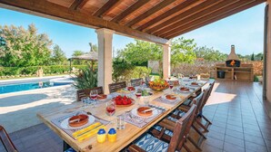 Area pranzo all'aperto con piscina, muro in pietra e forno a legna.