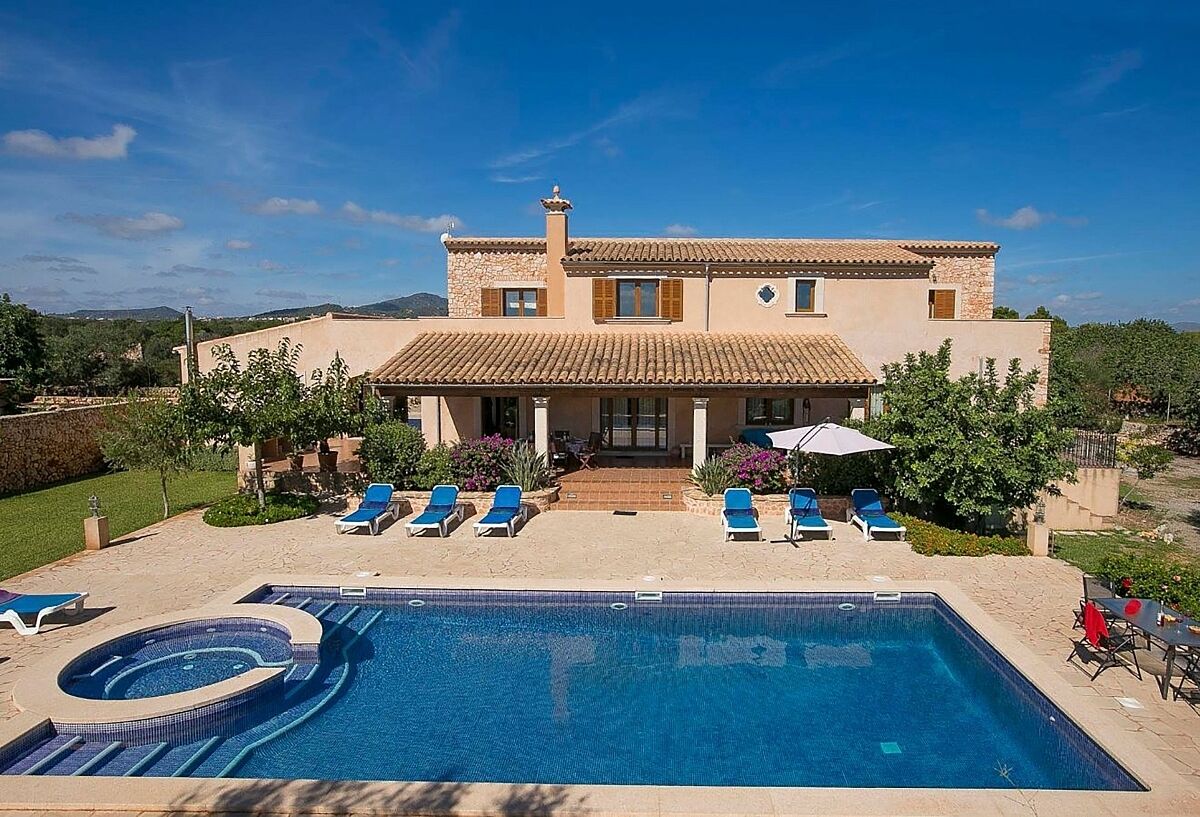 Ein zweistöckiges Haus mit Swimmingpool, Liegestühlen und einer Terrasse.