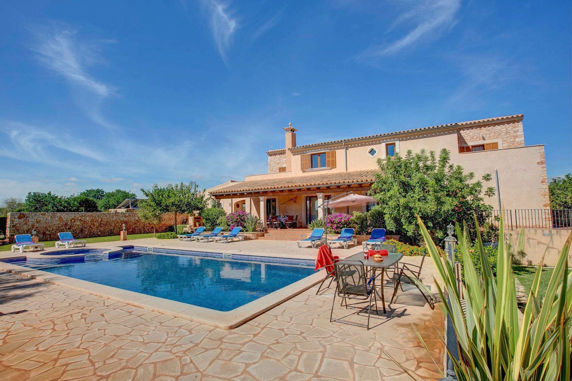 Une villa dotée d’une piscine, d’un espace extérieur aménagé et d’un mur en pierre.