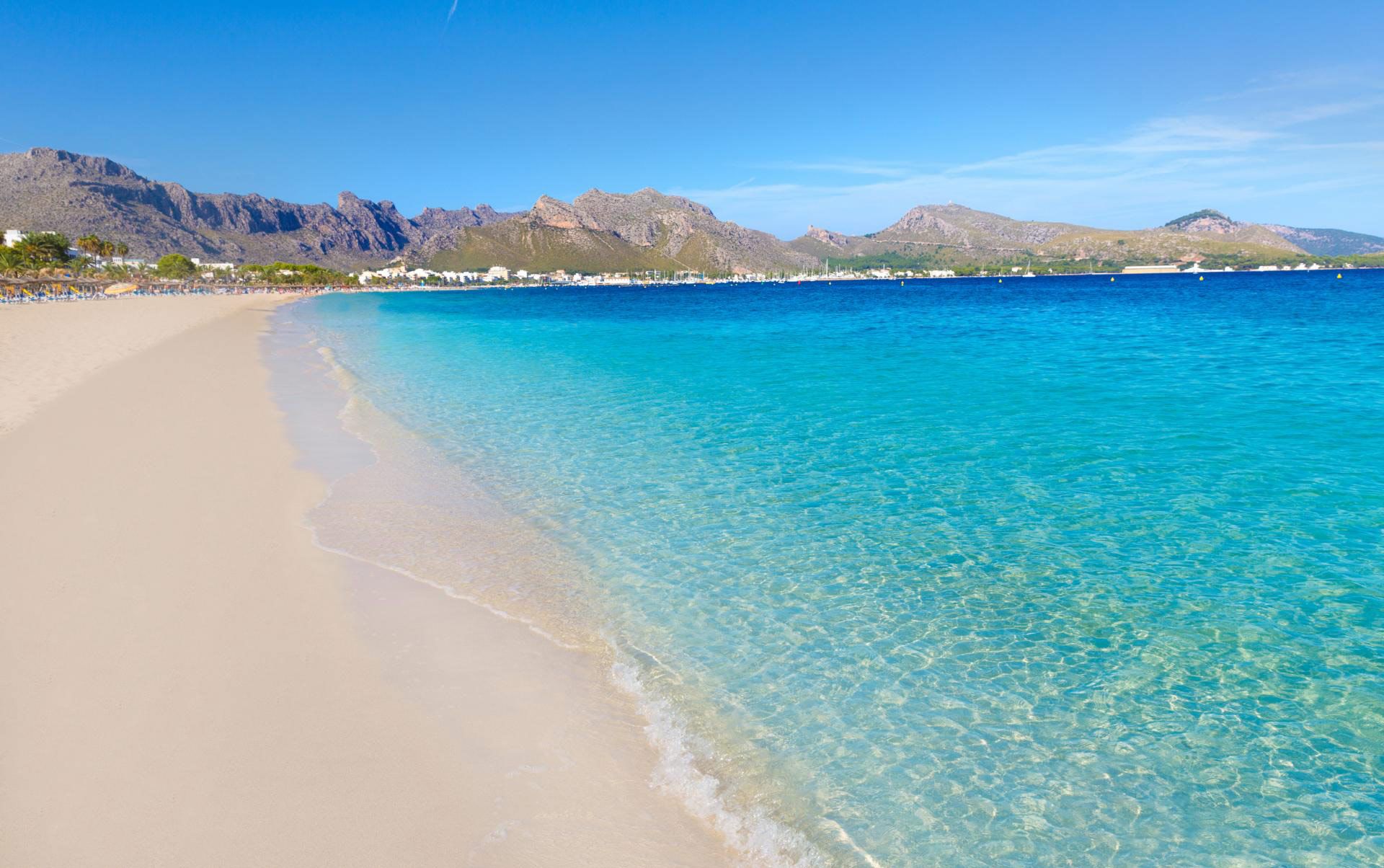 A beach with clear turquoise water and a sandy shore.