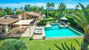 A large swimming pool with a stone deck, surrounded by lush greenery and palm trees. - Attractive Villa, A/C, Private Pool, Pretty Garden, Idyllic Setting close to Ancient Towns & Beaches (Alcudia)