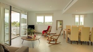 A modern living room with a glass door leading to a balcony, a dining area with a table and chairs, and a TV on a stand. - Modern Stylish Villa, A/C, Private Pool, Marina Views, 10mins walk to Cala d'Or & 2 Sandy Beaches! (Cala d´Or)
