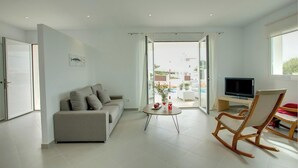 A modern living room with a sofa, a TV, a wooden rocking chair, and a glass door leading to a balcony. - Modern Stylish Villa, A/C, Private Pool, Marina Views, 10mins walk to Cala d'Or & 2 Sandy Beaches! (Cala d´Or)