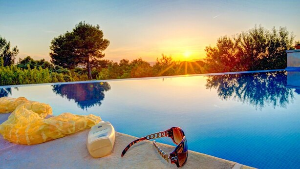 Ein Pool mit klarem Wasser, das Bäume und einen Sonnenuntergang reflektiert.