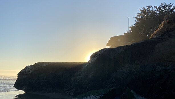 A coastal landscape with a cliff and beach during sunset. - The Boardwalk Beach House (Santa Cruz)