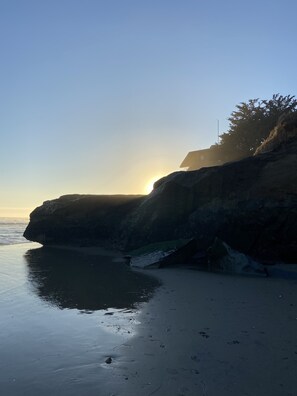 A coastal landscape with a cliff and beach during sunset. - The Boardwalk Beach House (Santa Cruz)