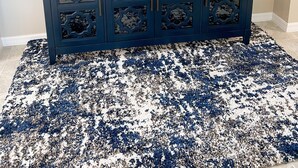 Un mobile scuro blu con decorazioni intagliate, uno specchio rotondo, un cartello incorniciato con la scritta 'family', una pianta in vaso, una lampada e due portacandele sulla sommità.