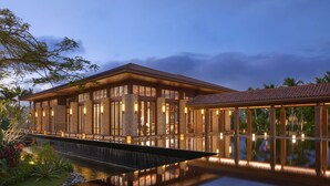 Un hotel modern amb una piscina reflectant, finestres grans i una façana ben il·luminada.