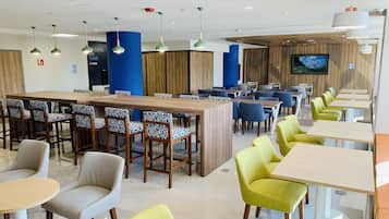 Ein modernes Restaurant mit Barbereich, Sitzgelegenheiten und einem Fernsehbildschirm.