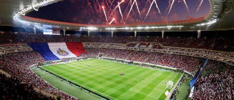A large stadium with a football field, surrounded by a crowd of spectators.
