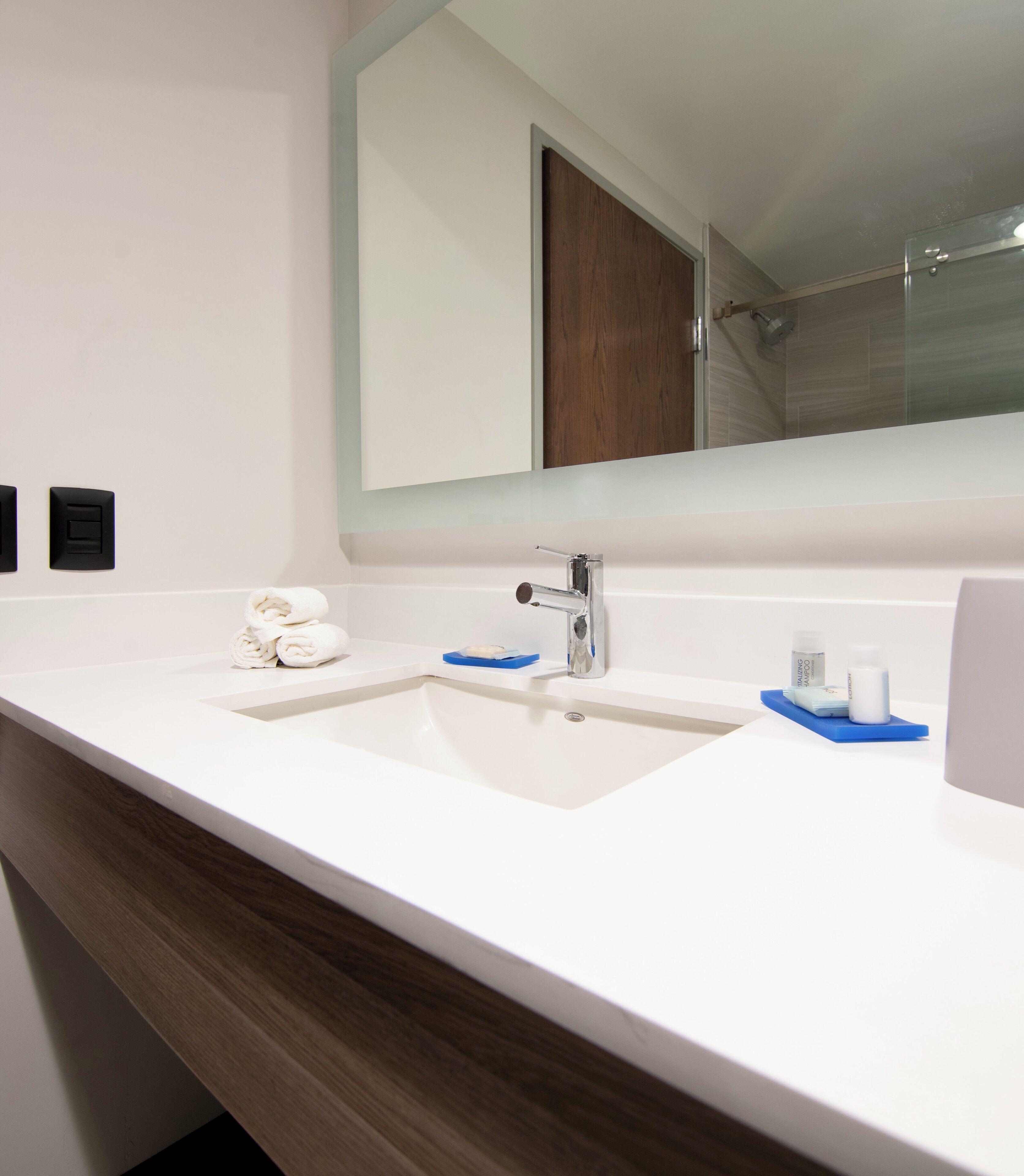 A bathroom with a white sink, a mirror, and a wooden vanity.