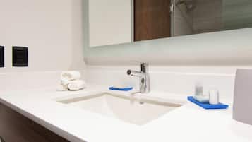 A bathroom with a white sink, a mirror, and a wooden vanity.