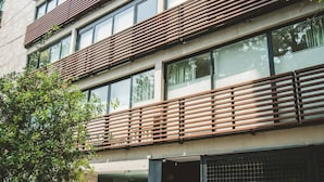 Un immeuble à plusieurs étages, doté d’un design moderne, avec des lambris en bois horizontaux sur les balcons et de grandes fenêtres.