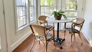 A room with a round table and four wicker chairs, a potted plant on the table, and large windows with white shutters. - Luxury Round Top Farmhouse  / 6mil to The Square (Round Top)