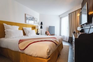 A hotel room with a large bed, a desk, a chair, a lamp, and a television. - Le Val Thorens (Les Belleville)