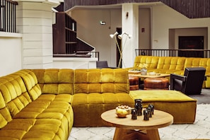 A modern interior with a sectional sofa, a round wooden table, and a staircase.