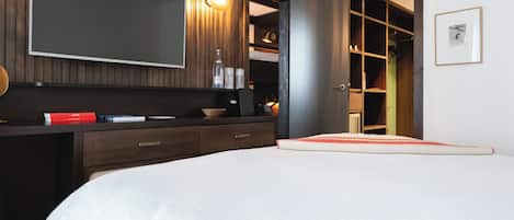 A bedroom with a bed, a dresser, a mirror, and a wardrobe.