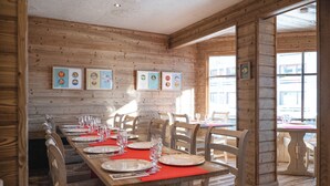 A wooden interior with a long dining table set for a meal, wooden walls, and framed pictures on the wall. - Le Val Thorens (Les Belleville)