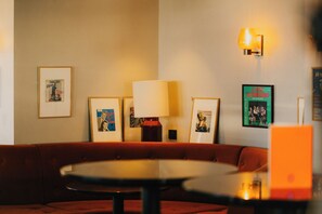 A room with a red sofa, a round table, framed pictures on the wall, and a lamp. - Le Val Thorens (Les Belleville)