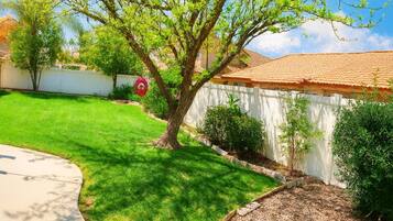 Una propiedad residencial con un césped cuidado, un árbol y una cerca blanca.