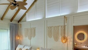 A spacious room with two wooden beds, a ceiling fan, and a bathroom with a round mirror.
