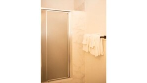 Une salle de bain avec une porte de douche en verre, un porte-serviettes avec des serviettes blanches et un mur en marbre.