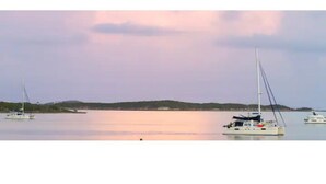 Un port tranquille, avec des voiliers et une côte lointaine.