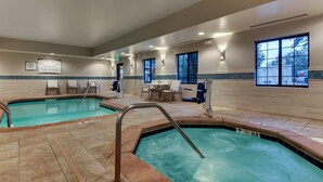Un área de piscina con dos piscinas, sillas de descanso y un cartel que indica que no hay socorrista de servicio.