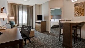 Habitació d'hotel amb escriptori, cadira, llit, televisió i zona de dinar.