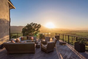 Terraza con sofá y sillones, con vistas a un paisaje pintoresco al atardecer.