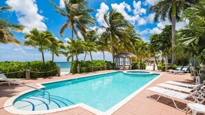 A pool area with lounge chairs, a gazebo, and palm trees. - Kaibo Kove (Rum Point)