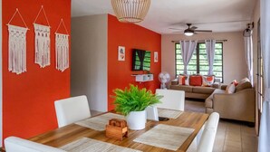 A dining area with a wooden table, white chairs, and a central plant. - A Slice of the Rainforest! Near El Yunque and Beaches, Rio Grande Puerto Rico (Rio Grande)
