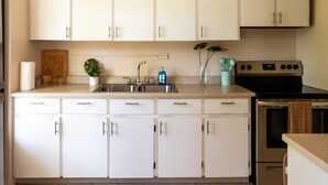 A modern kitchen with white cabinets, a stainless steel stove, and a sink. - A Slice of the Rainforest! Near El Yunque and Beaches, Rio Grande Puerto Rico (Rio Grande)